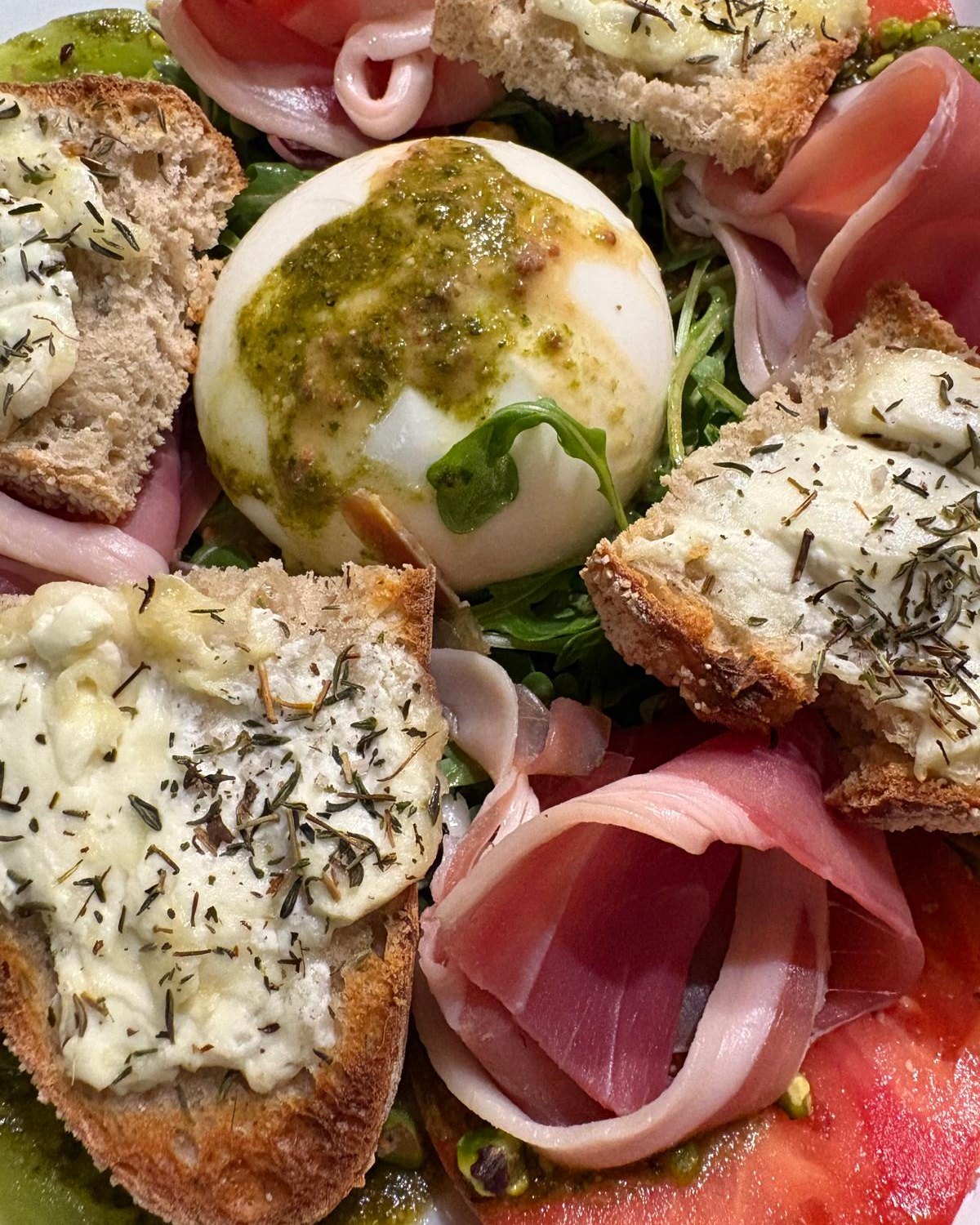 Salade burrata : burrata au pesto, jambon cru, roquette, tomates et toasts de chèvre chaud